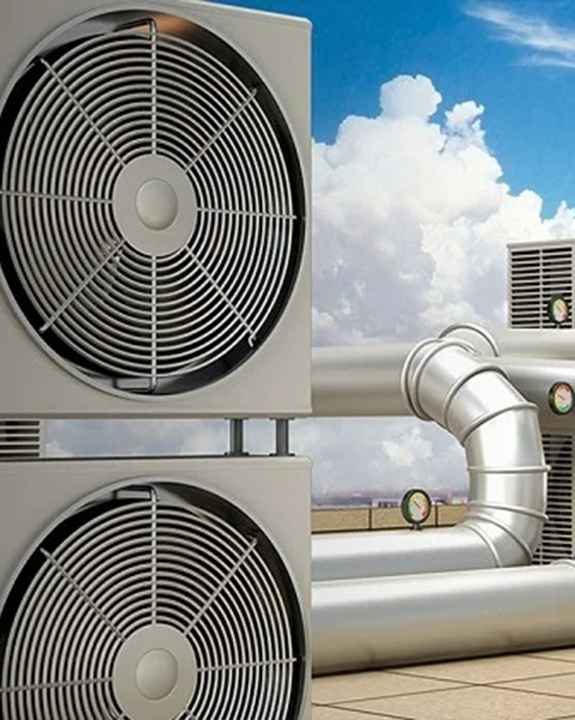 Large industrial HVAC units with visible fans and ductwork are installed outdoors on a rooftop under a partly cloudy sky, highlighting the importance of regular ac repair for optimal performance.