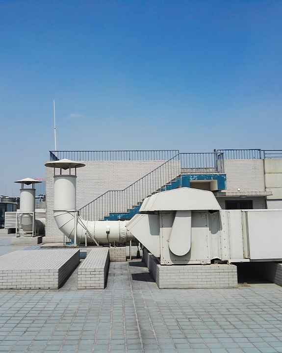 Rooftop view with ventilation systems, white brick structures, railings, and a clear blue sky in the background—ideal for routine maintenance or ac repair.